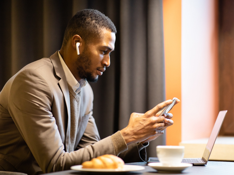 man wearing headphones while looking at phone